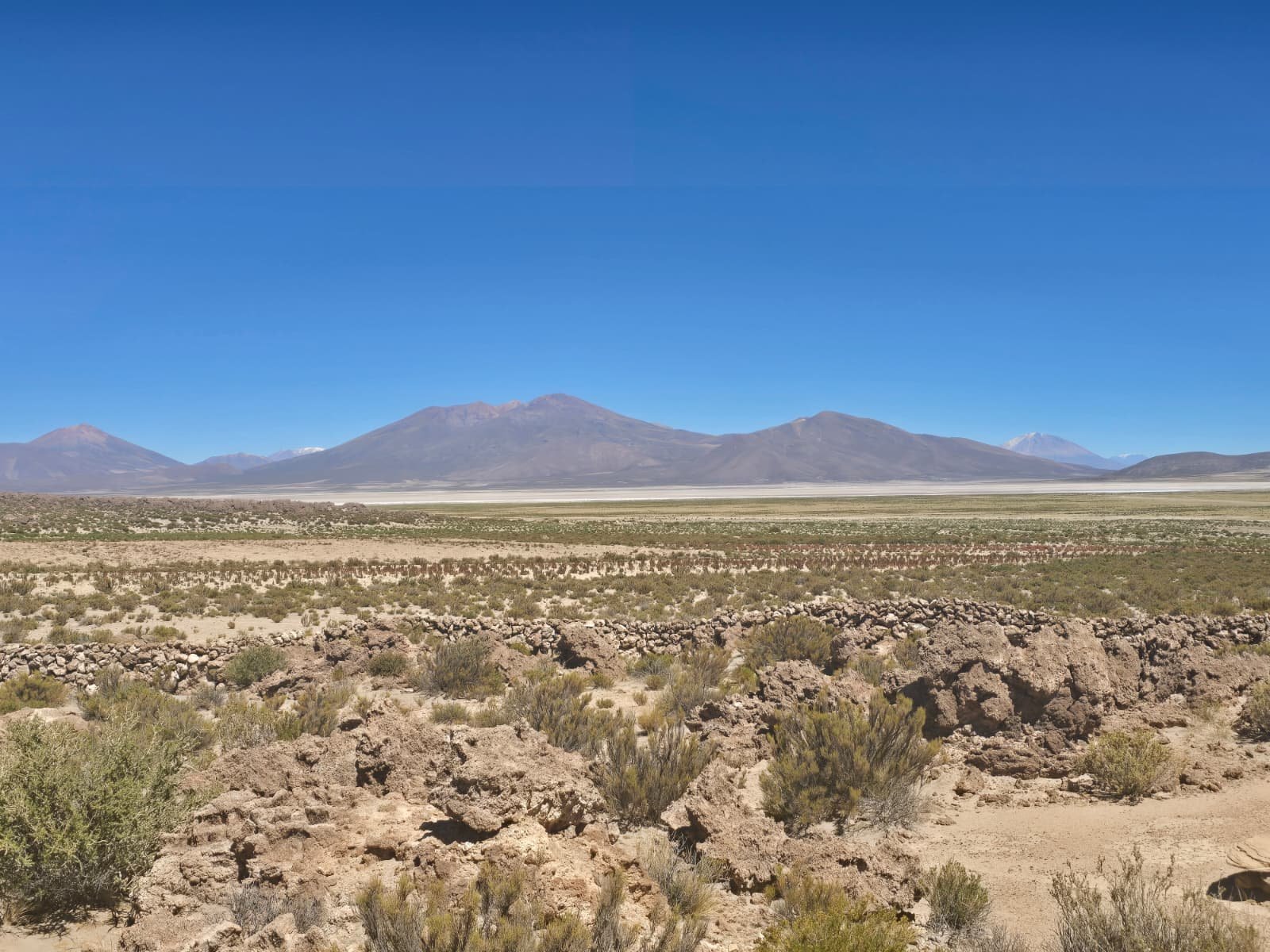 Altiplano panorama with Salar de Uyuni on the horizon between volcanoes